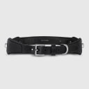 A dog collar in smooth, natural bovine leather, handmade in a Polish artisan workshop. Designed by the Italian designer Francesco Rigucci, it is recognisable by its signature shape and the jewellery-like metal studs carrying the brand logo. The outer layer is black vegetable-tanned bovine leather with matching black stitching, over soft padding and a black leather lining. The D-ring, buckle and logo studs are solid brass in gunmetal finish, nickel-free and protected with a durable polished coating. Adjustable length – check the measurements to choose the right size for your dog. Available on its own or as a set with the matching leather leash and lambskin gloves.