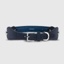 A dog collar in vegan cactus leather, handmade in a Polish artisan workshop. Designed by the Italian designer Francesco Rigucci, it is recognisable by its signature shape and the jewellery-like metal studs carrying the brand logo. The outer layer is navy cactus leather with matching navy stitching, over soft padding and a cobalt cactus leather lining. The D-ring, buckle and logo studs are solid brass in silver finish, nickel-free and protected with a durable polished coating. Adjustable length – check the measurements to choose the right size for your dog. Available on its own or as a set with the matching cactus leather leash.