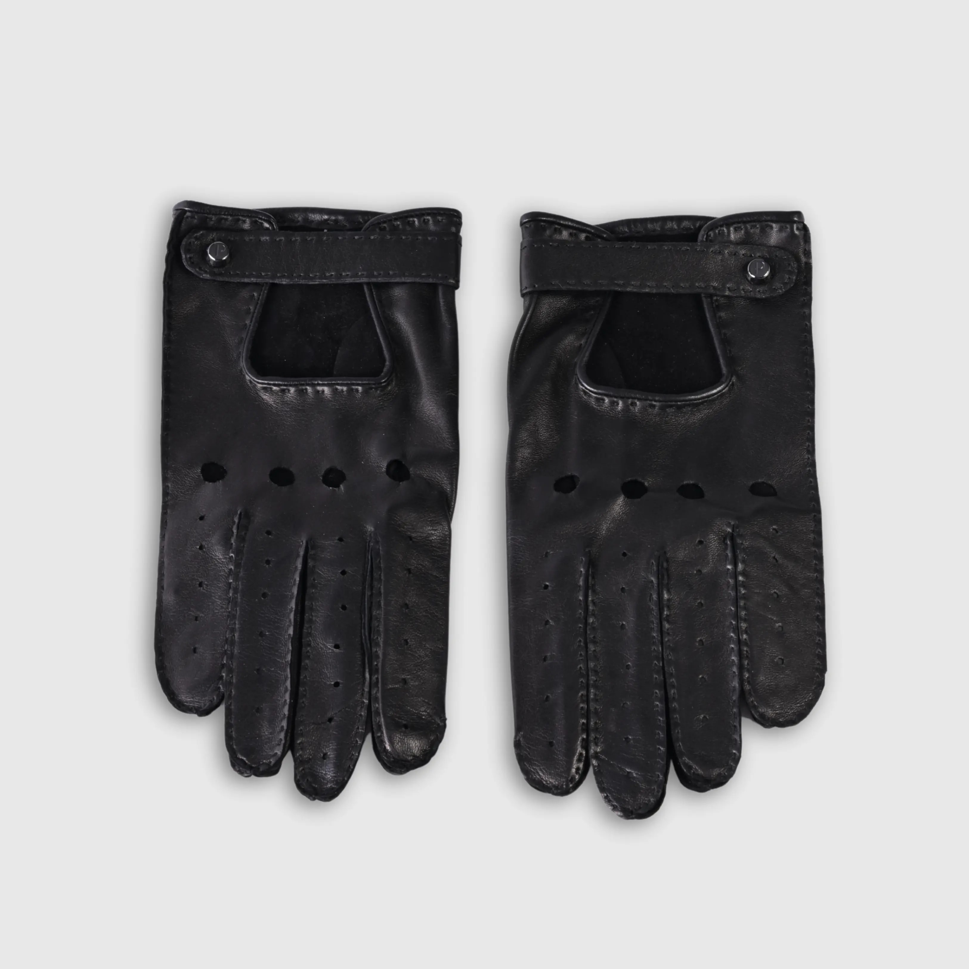Gloves in natural black lambskin, made in an Italian artisan workshop. Designed by the Italian designer Francesco Rigucci. Entirely hand-sewn from smooth lambskin, prized for its exceptional softness. They are unlined, which makes them just as wearable on milder days. The cut-out at the wrist gives them their modern shape. The signature solid brass fastening comes in gunmetal finish, nickel-free and protected with a durable polished coating. Available in sizes 7, 7.5, 8, 8.5, 9 and 9.5 (the size matches the hand circumference in inches).