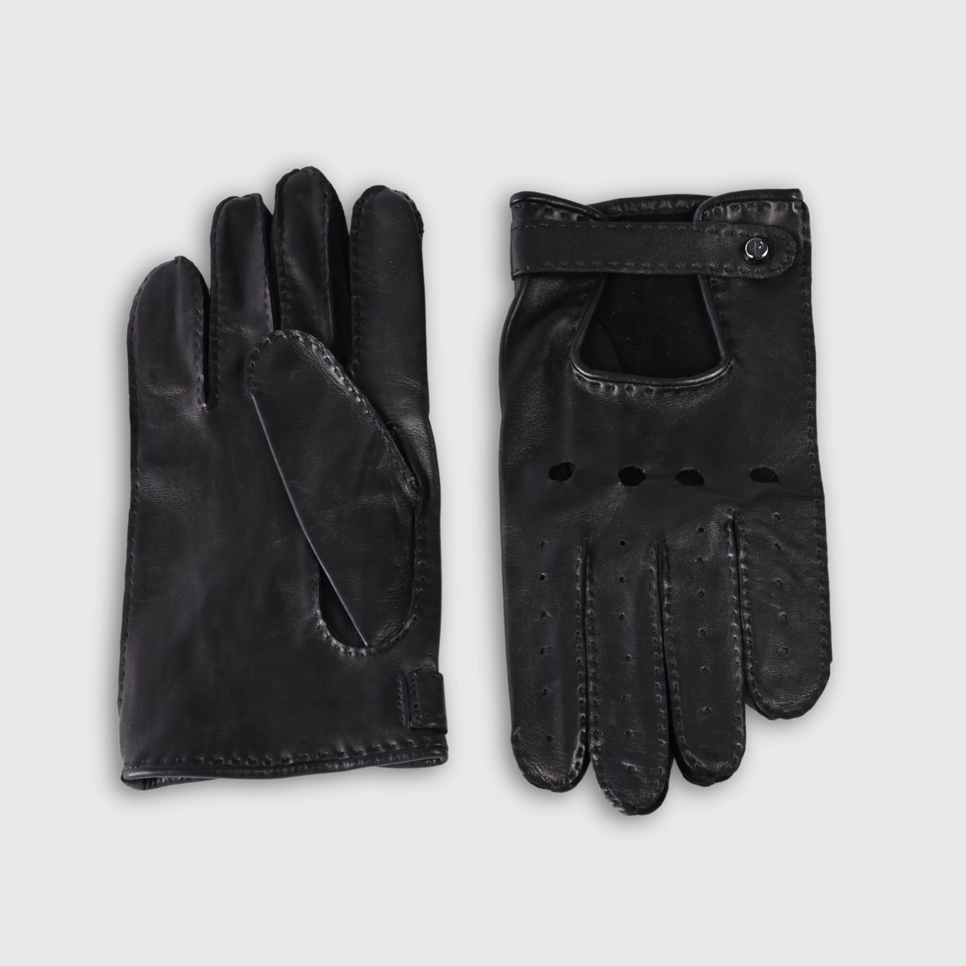 Gloves in natural black lambskin, made in an Italian artisan workshop. Designed by the Italian designer Francesco Rigucci. Entirely hand-sewn from smooth lambskin, prized for its exceptional softness. They are unlined, which makes them just as wearable on milder days. The cut-out at the wrist gives them their modern shape. The signature solid brass fastening comes in gunmetal finish, nickel-free and protected with a durable polished coating. Available in sizes 7, 7.5, 8, 8.5, 9 and 9.5 (the size matches the hand circumference in inches).