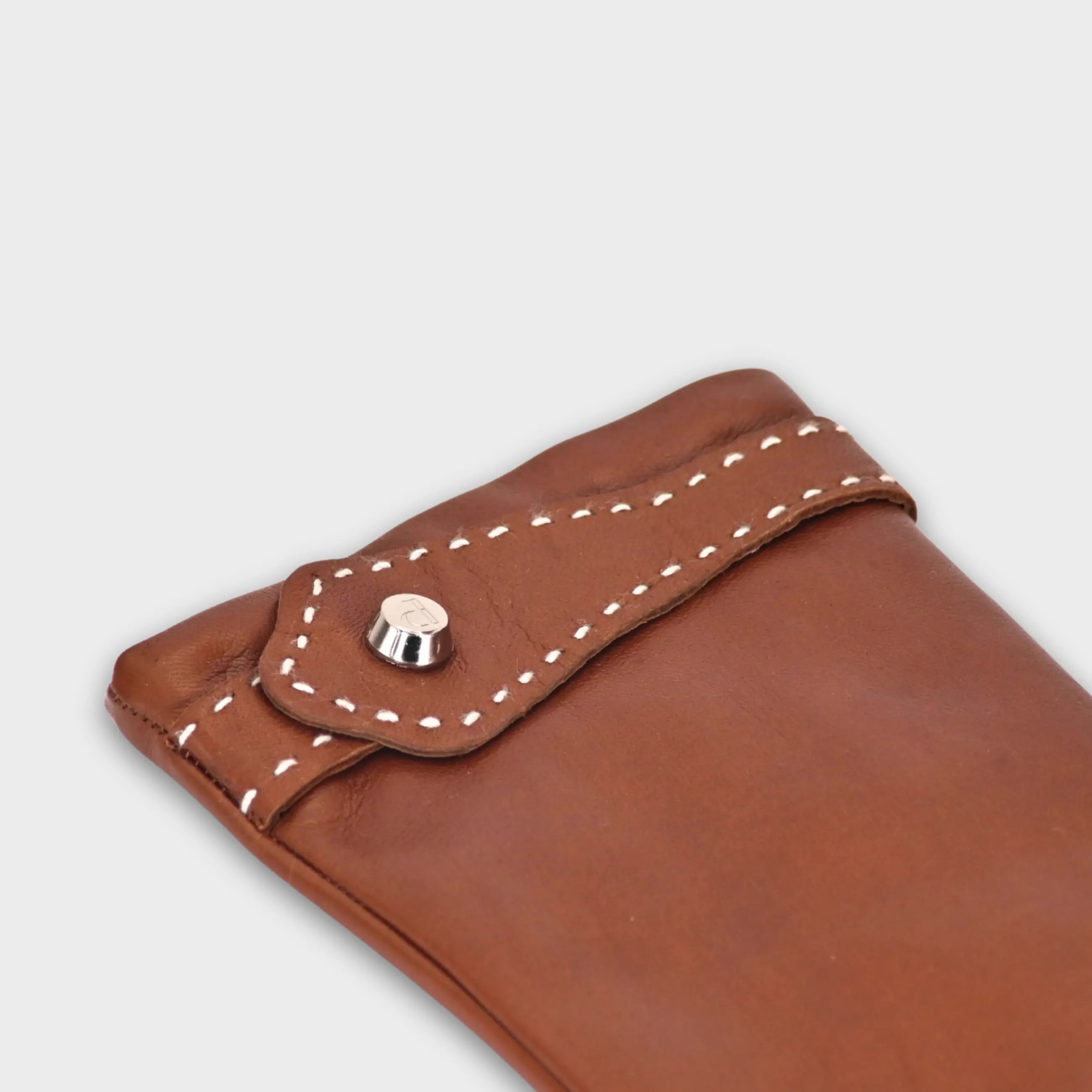Handcrafted from smooth caramel lambskin and lined with natural beige cashmere. Finished with a decorative, hand-stitched leather strap in contrasting beige thread. Featuring the signature brass logo closure in silver, nickel-free and protected with a durable, polished finish. Made in an artisanal workshop in Italy. Available in sizes 7, 7.5, 8, 8.5, 9, 9.5 (Italian sizing).
