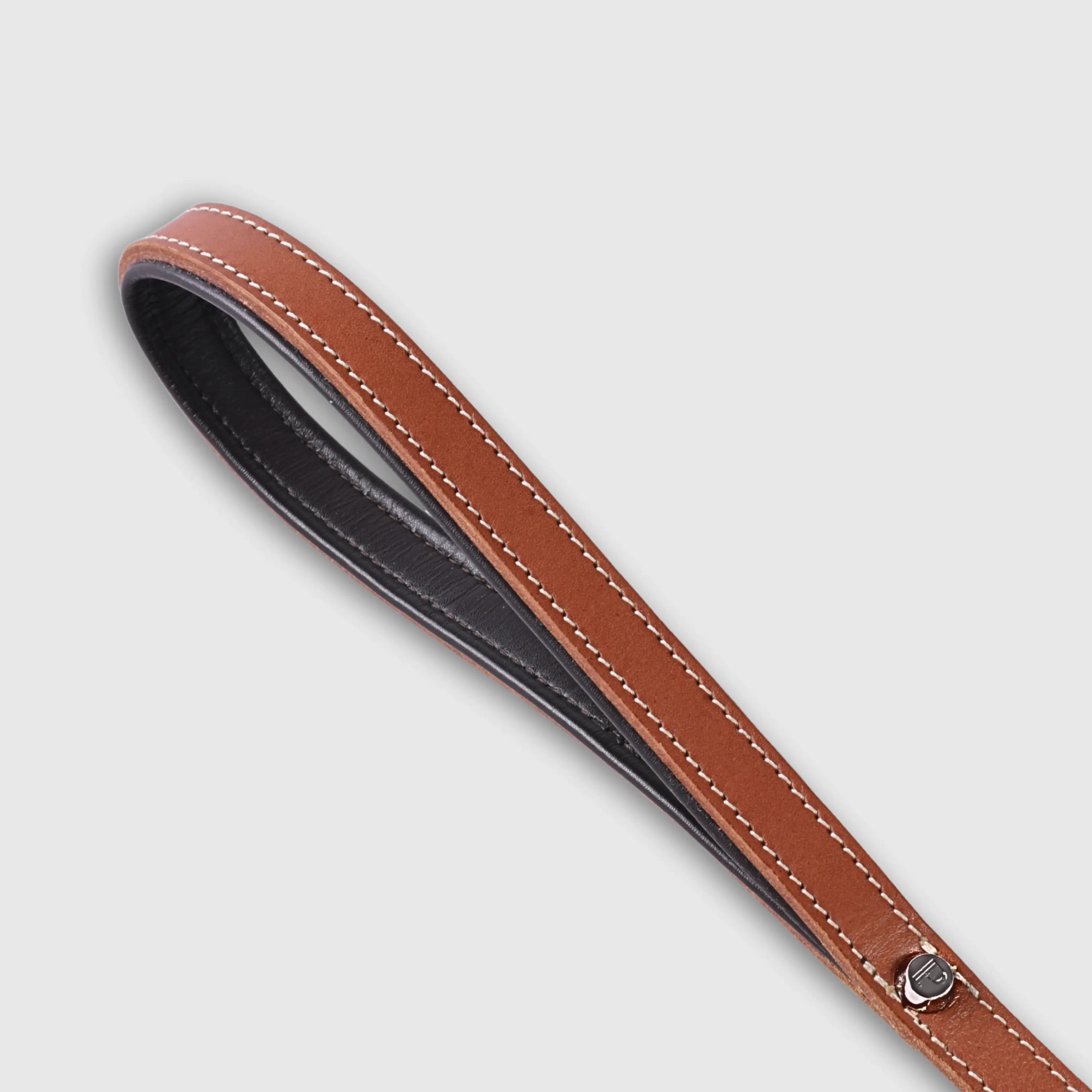 Hand-stitched from smooth, natural calfskin in an artisan workshop in the EU. Characterized by Pattmond’s signature shape, distinguished by subtle shifts in width and refined ornamental details. Caramel-coloured, vegetable-tanned leather with beige contrast stitching and a brown lining inside the handle. Solid brass hardware in silver (signature snap hook and logo studs), nickel-free and protected with a durable, polished finish. With a fixed length of 175 cm and a width of: - 1.5 cm, it is proportioned for smaller and medium dogs - 2.2 cm, it is proportioned for larger dogs.