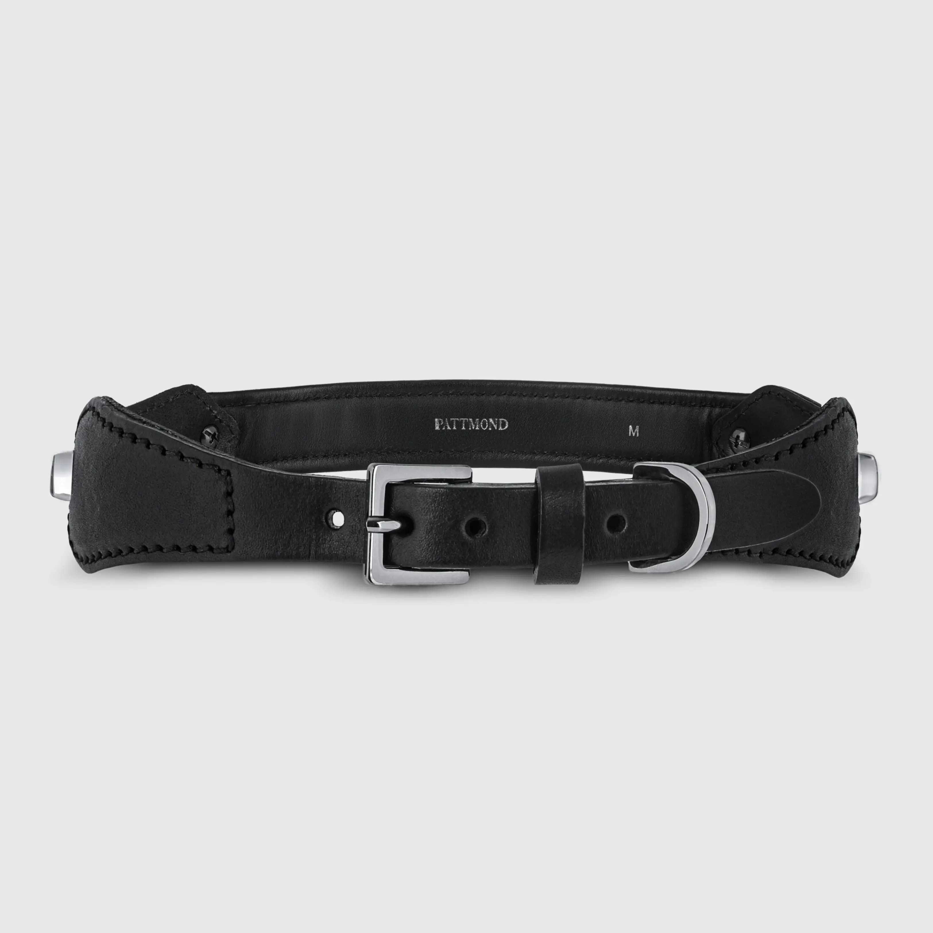 Hand-stitched from smooth, natural calfskin in an artisan workshop in the EU. Characterized by Pattmond’s signature shape, distinguished by subtle shifts in width and refined ornamental details. Black, vegetable-tanned leather exterior with matching black stitching and black leather lining. Solid brass hardware with a gunmetal finish (D-ring for the leash, buckle and signature logo studs), nickel-free and protected with a polished finish. Adjustable length (see dimensions to choose the best fit for your dog). Available individually or in a set with a matching leather leash and gloves (made from lambskin).