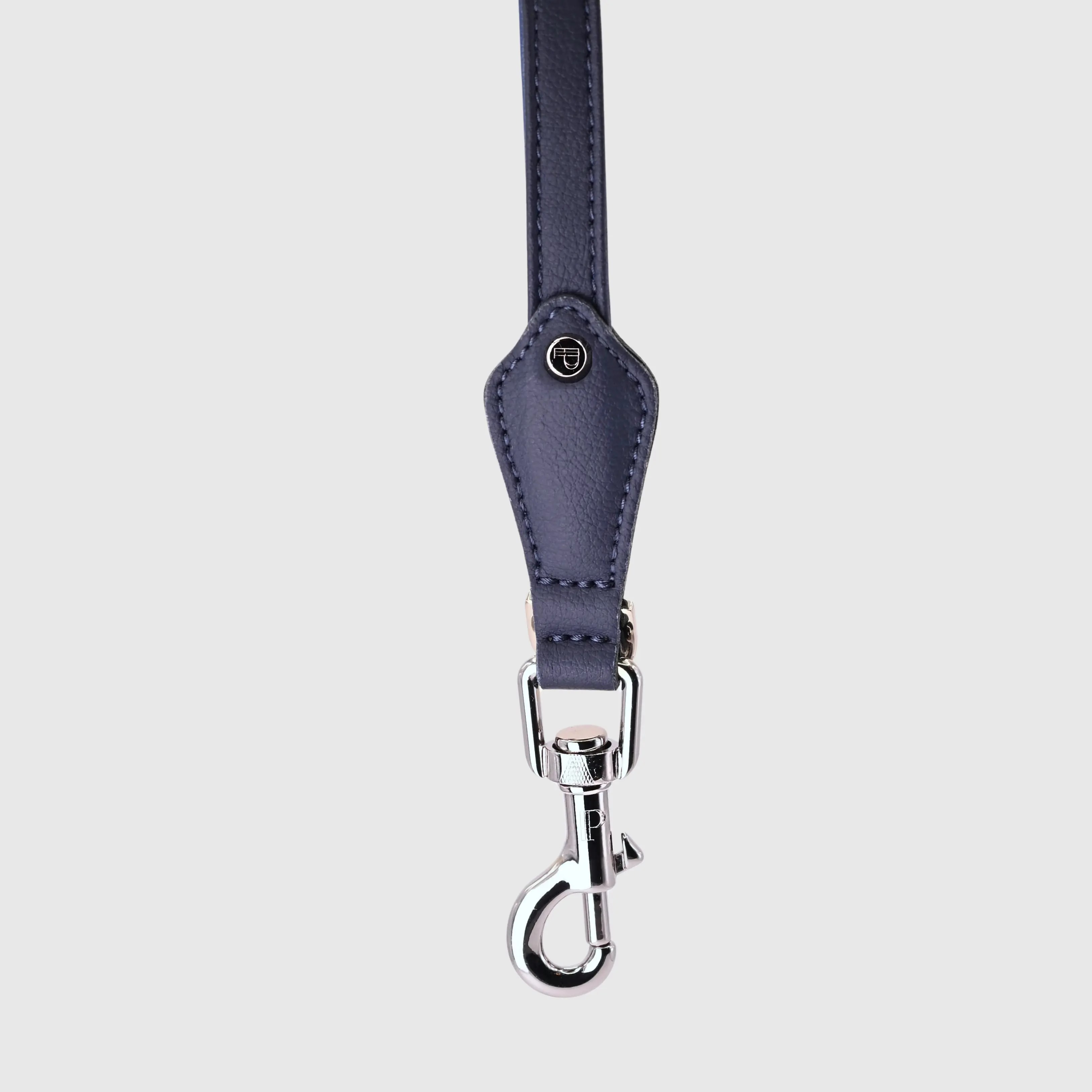Hand-stitched from grained, cactus vegan leather in an artisan workshop in the EU. Characterized by Pattmond’s signature shape, distinguished by subtle shifts in width and refined ornamental details. Navy cactus-based leather with matching navy stitching. Solid brass hardware in silver (signature snap hook and logo studs), nickel-free and protected with a durable, polished finish. Adjustable length of 230 cm, 150 cm, and 115 cm. With a width of 2.2 cm, it is proportioned for larger dogs.
