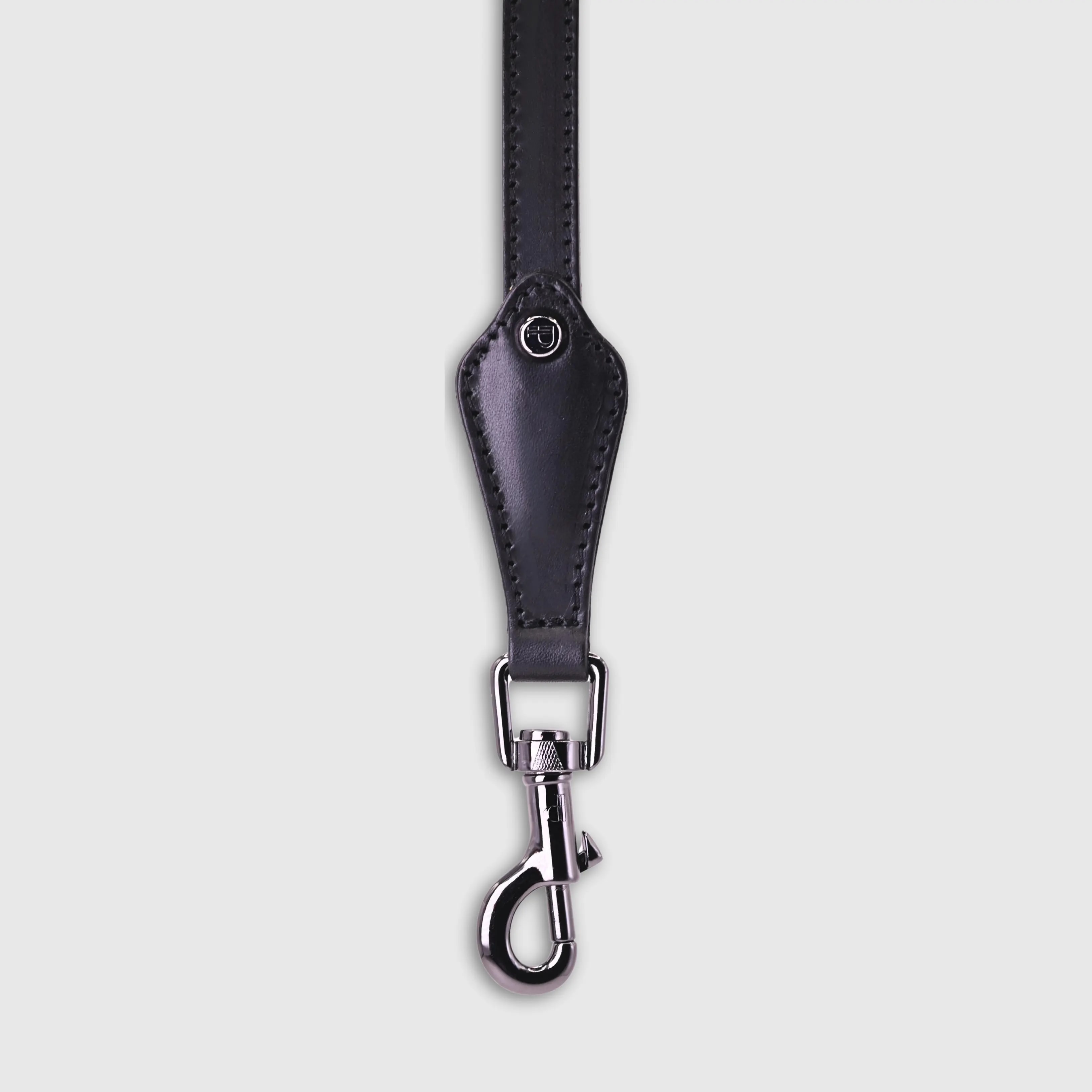 A dog leash in smooth, natural bovine leather, handmade in a Polish artisan workshop. Designed by the Italian designer Francesco Rigucci, it is recognisable by its signature shape and the jewellery-like metal studs carrying the brand logo. Made from black vegetable-tanned bovine leather with matching black stitching. The handle is finished with a black leather lining. The snap hook and logo studs are solid brass in gunmetal finish, nickel-free and protected with a durable polished coating. Fixed length of 175 cm. Available in two widths: 1.5 cm and 2.2 cm. Available on its own or as a set with the matching leather collar and lambskin gloves.