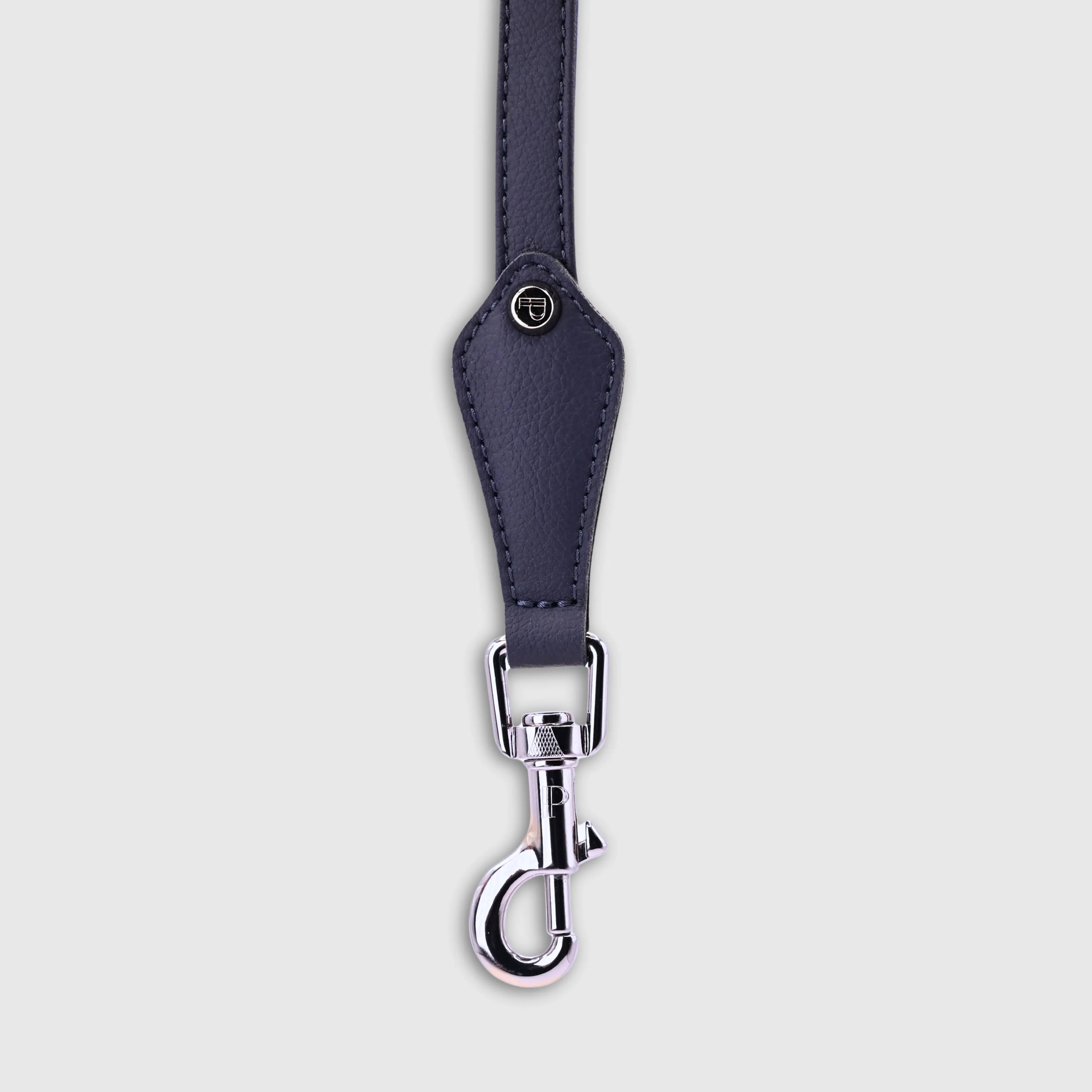 A dog leash in vegan cactus leather, handmade in a Polish artisan workshop. Designed by the Italian designer Francesco Rigucci, it is recognisable by its signature shape and the jewellery-like metal studs carrying the brand logo. Made from navy cactus leather with matching navy stitching. The handle is finished with a cobalt cactus leather lining. The snap hook and logo studs are solid brass in silver finish, nickel-free and protected with a durable polished coating. Fixed length of 175 cm. Available in two widths: 1.5 cm and 2.2 cm. Available on its own or as a set with the matching cactus leather collar.