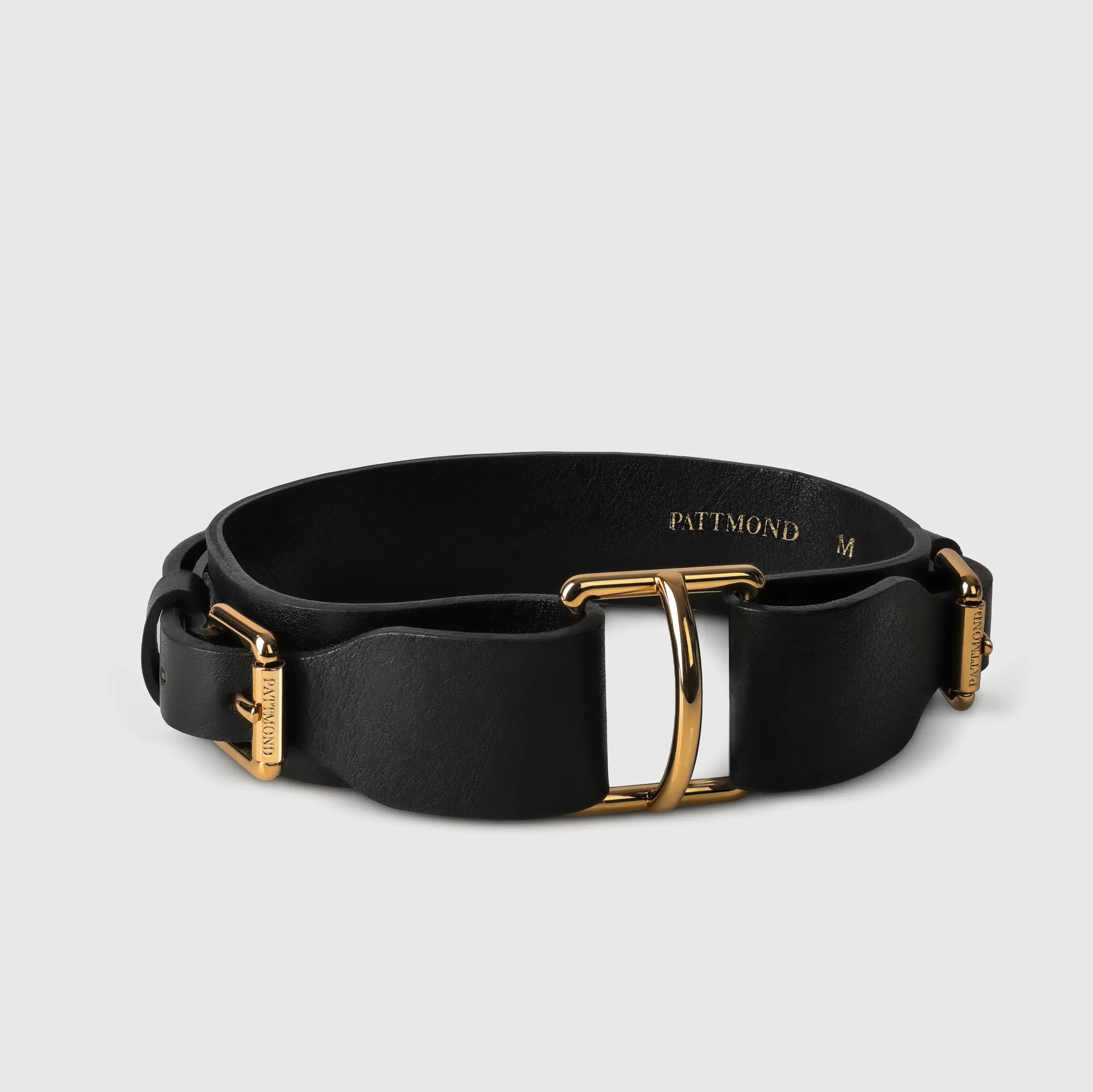 A dog collar in natural bovine leather, hand-sewn in a Polish artisan workshop. Raw edges and clean lines bring out the natural character of vegetable-tanned leather. The collar is defined by its solid brass hardware, nickel-free and made to order for Pattmond by an Italian manufacturer. The polished gold finish gives it a jewellery-like quality. A distinctive metal piece at the centre of the collar makes clipping on the leash easy, and two side buckles with the Pattmond logo allow a precise fit. Available on its own or as a set with the matching leather leash.